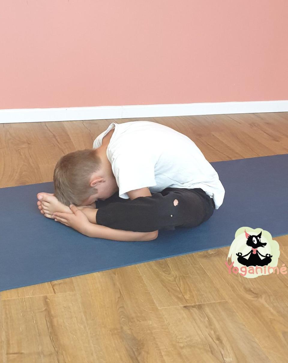 Un enfant fait la posture de yoga la tortue
